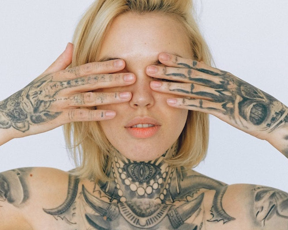 Eine stilvolle Dame mit einem Körper voller detaillierter Tattoos, die ihre einzigartige Kunst und Persönlichkeit zur Schau stellt. Ausdrucksstark und selbstbewusst.