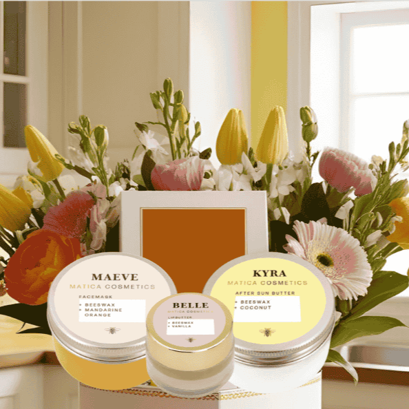 After-Sun Bodybutter, Lipbalm und Gesichtsmaske im Vordergrund, mit einem zarten Blumenstrauß im Hintergrund. Perfekt für entspannende Selfcare-Momente zum Muttertag.