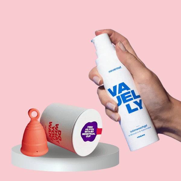 nevernot Periodenpflege Set: Menstruationstasse liegt neben VAJELLY Intimwaschgel, das in der Hand gehalten wird – sanfte, hygienische Pflege für die Periode, vegan und pH-balanced.